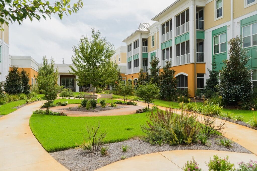 Exterior image of The Arbors of Gulf Breeze private courtyard with walking paths, beautiful scenery, and various seating throughout the garden.