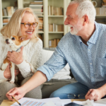 April 25 Events Page Image - The Arbors of Gulf Breeze Elderly man and woman smiling and holding small dog