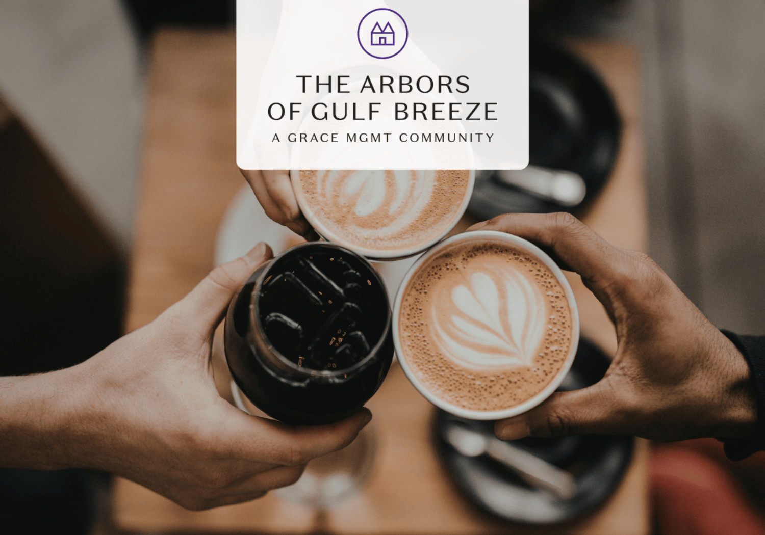 Overhead shot of three people clinking coffee cups, latte art on two cups, with a translucent overlay reading 'The Arbors of Gulf Breeze'.